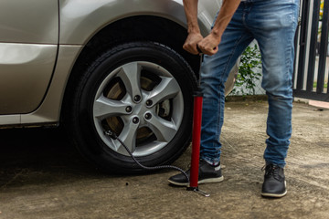  Topic of problems with the car on the road. man with manual inflator pump inflating car tire. roadside assistance concept