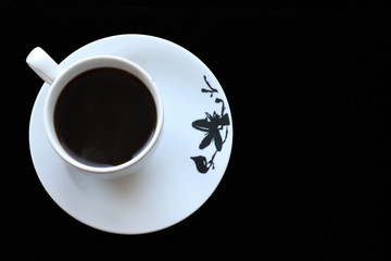 White cup with black coffee on black background. Top view with copyspace for your text