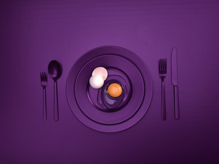Purple dishes with a broken egg and shell on a plate. Ceramic dishes with a fork, spoon and knife. For cafes, posters, breakfasts and dinners. Copyspace for your individual text