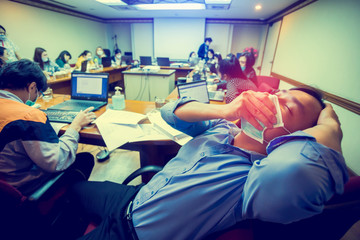 A businessman wearing a mask and coughing in meeting  room.