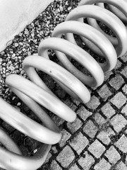 Spiralfeder aus Metall, Spiralfeder auf Asphalt, Spiralfeder Nahaufnahme, Spiralfeder schwarz weiß, Feder Spirale, Autoersatzteil