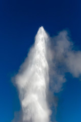 Fototapeta na wymiar The top of Old Faithful geyser shooting into the air at Yellowstone Park Wyoming with a blue sky