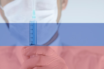 The doctor is holding the syringe with blue liquid in the glove. Close-up. Syringe focused.