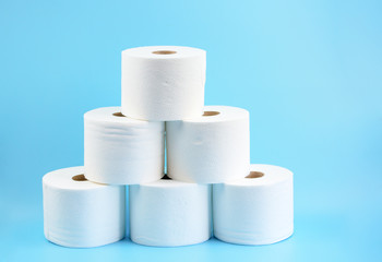 Toilet paper stacked rolls on a blue background. A pile of white toilet rolls to illustrate the issue of out of stock loo roll in stores.Toilet paper crisis due to coronavirus COVID-19 quarantine.