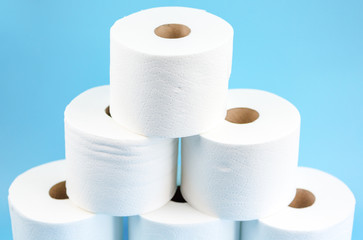 Toilet paper stacked rolls on a blue background. Toilet paper crisis due to coronavirus COVID-19 quarantine. Close up view.