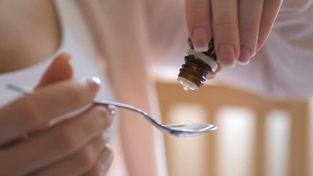 Sick child concept. Mother drops medicine on a spoon