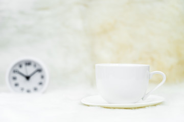 Cup of coffee with alarm clock on table