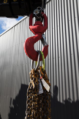 Detail of a red hook, shackle and chain.  Part of a mobile crane for lifting heavy goods and...