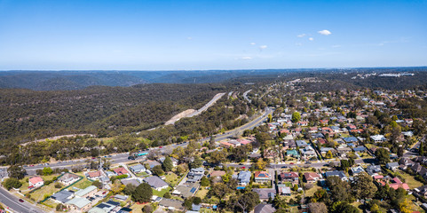 Aerial drone photo of Kuring Gai Chase National Park, Berowra and the Pacific Highway and M1 Motorway, Mount Kuring Gai (distant right) and Sydney CBD to the horizon on a clear sunny day.