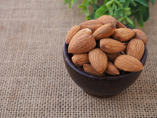  Almonds seeds in wooden bowl on sackcloth background.