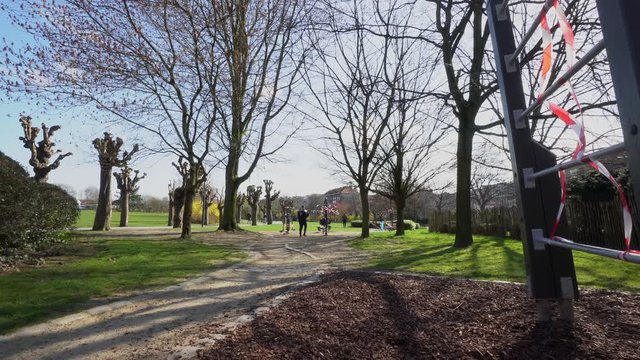Wide shot of empty parc with windy trees and fitness equipment wrapped with cordon tape by the police because of Corona.