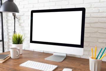 Mockup blank screen computer on a wooden desk. desktop empty white screen, with workspace and office supplies on table