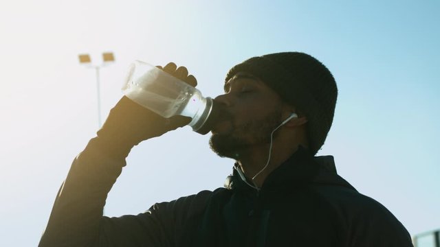 A thirsty dark skin sportsman drinking water in slow motion