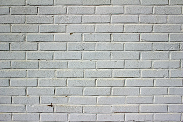 Dingy white painted brick wall texture with peeling and staining