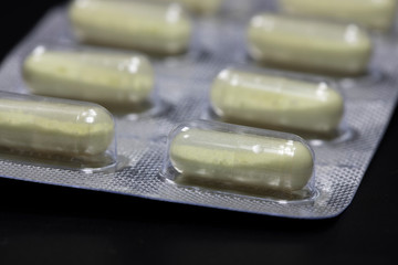 Yellow round pills in a package on a black background.