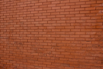 Vintage burnt orange color brick wall background with grungy texture (angle view)