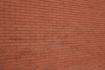 Vintage burnt orange color brick wall background with grungy texture (angle view)