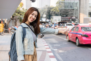 Smiling young Asian travel girl hitchhiking on the road in city. Life is a journey concept.