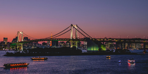 Tokyo skyline, Rainbow bridge, Tokyo Tower and Sumida river with boats and reflections at sunset, Japan