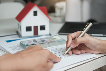 Customers are reading loan and insurance agreement documents to sign real estate transactions.