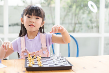 happy beautiful girl playing chess on wood table floor at home.