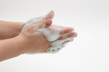 Hands of child on a white background in white foam from antibacterial soap