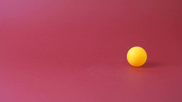 Yellow tennis ball jumping on a red background. Hand takes the ball. Table tennis. Hobbies for relaxation. Sport. Jumping object.
