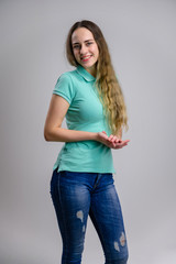 Vertical photo of a smiling pretty young woman with long hair in a turquoise blue jeans blouse on a white background.