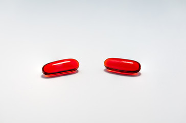 Two red capsule tablet pills medication on plain white background. Cure and treatment concept.