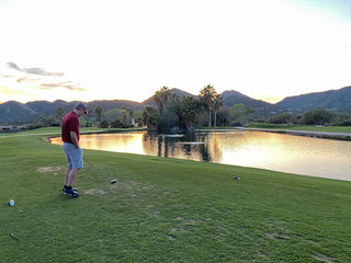 man golfer mountains lagoon sunset tee box