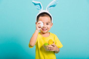 child boy wearing bunny ears and yellow T-shirt, standing to holds easter eggs instead of eyes