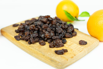 brown raisins on a wooden board on a white background