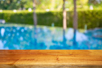 Display products on a brown wooden table by the pool.