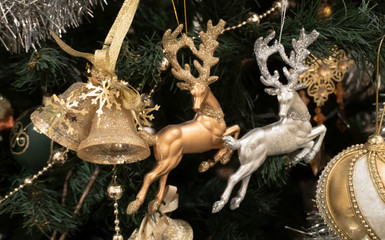 Christmas tree toys. Two deer of different colors and bells. Amid foliage