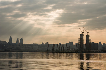 Panorama of the city of Baku and the Baku Bay on a cloudy day at sunset. The sun's rays Shine through the clouds on the sea surface.