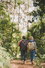Rear view of young couple walking through woods  Man and woman hiking in forest.