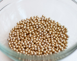Close up of little golden balls in a clear transparent bowl.