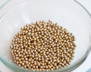 Close up of little golden balls in a clear transparent bowl.