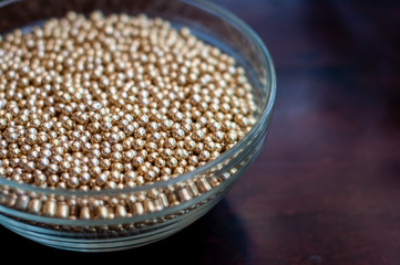 Close up of little golden balls in a clear transparent bowl.