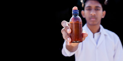 The young doctor holds the urine or other sample on a black background