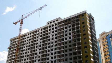 Fototapeta na wymiar Construction crane near the building under construction against the blue sky