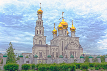 Fototapeta na wymiar Golden domes of Savior Transfiguration Cathedral. Cathedral fenced by a stone fence. Russia, Abakan