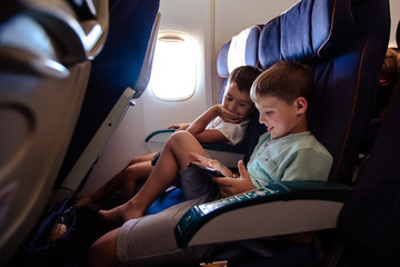 Leisure on the plane two boys play a tablet on a long flight.