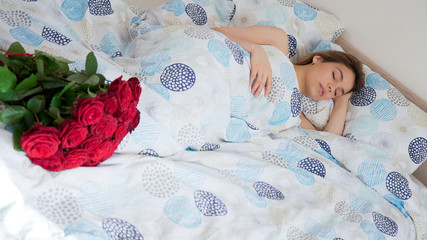 Obraz na płótnie Canvas Beautiful woman sleeping in bed. Surprise red rose bouqet waiting for her. Flower delivery. Romantic concept for valentines day, international womens day, engagement and birthday.