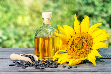 Bottle of sunflower oil and sunflower flowers with seeds on wooden table