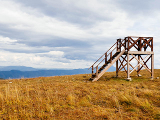 Fototapeta premium Wooden lookout tower in the mountains copy space. Observation point for forest fires. The concept of solitude , freedom, calmness, contemplation. Natural mountain background. Screensaver for the site