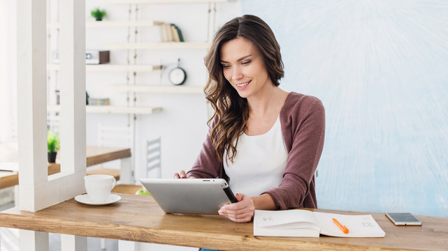 Young Beautiful Woman Using Digital Tablet At Home, Cheerful Smiling Girl Sitting At Her Workplace, Technology, Business, Home Work, Online Learning, Studying Concept, Distance Education