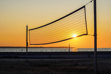 Sillhouette of a volleyball net against sunset on the beach