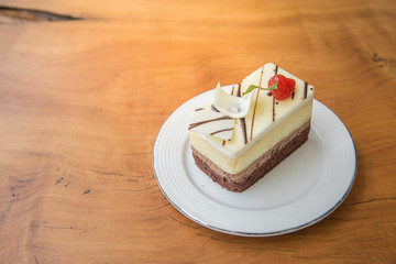 Fresh strawberry cheesecake on wooden table background. Selective focus on the front upper edge of the cake. © Possathorn
