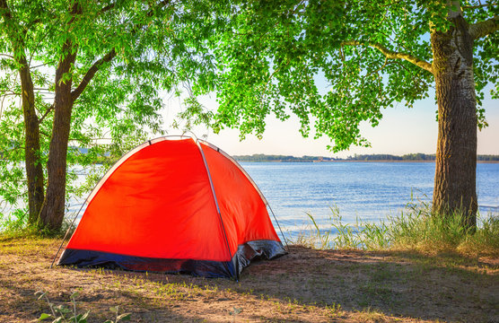 Red tourist tent on lake in summer